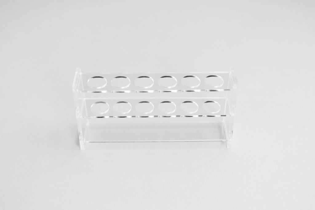 An acrylic display stand by itself on white with 6 holes to display essential oil roller bottles, lip gloss, or make up brushes