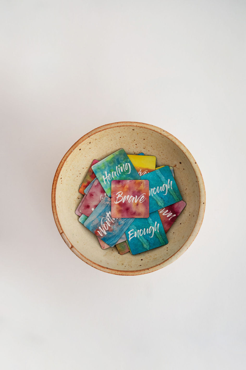 A pottery bowl filled with watercolor mini affirmation magnets