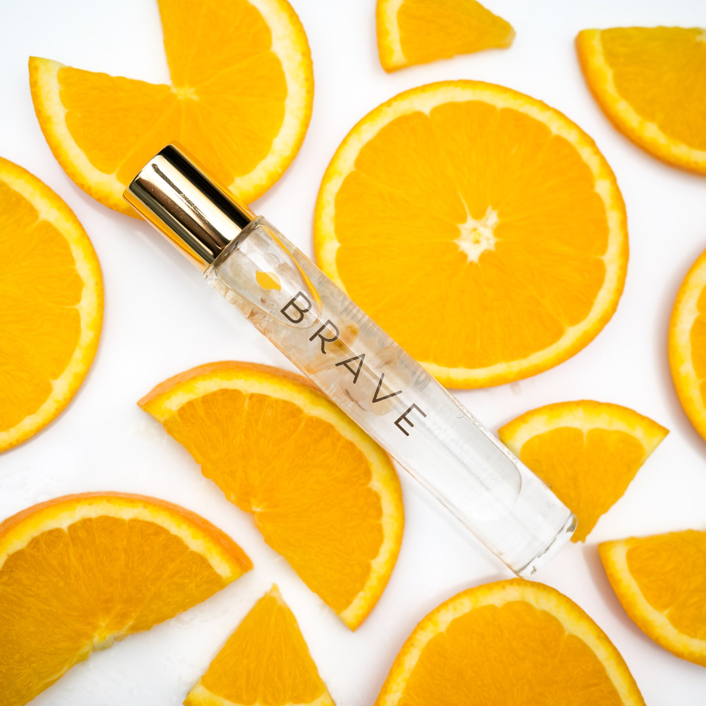 A Brave Crystal Essential Oil Roller Bottle Blend with citrine with fresh sliced oranges
