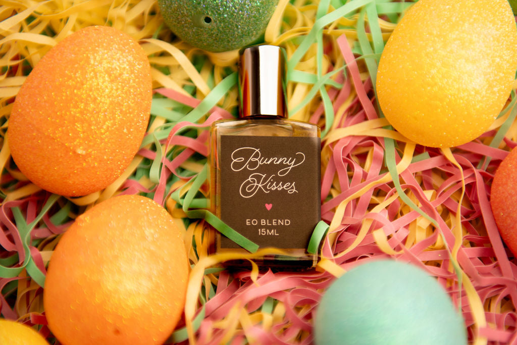 Bottle of Bunny Kisses essential oil blend with Easter eggs and colorful Paper shreds in an Easter Basket