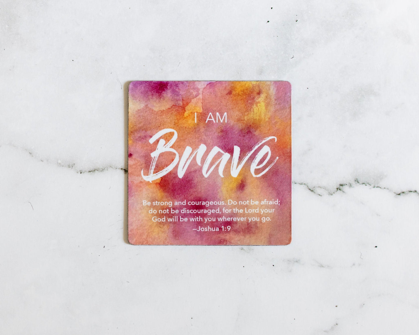 A Pink and Orange magnet that says I Am Brave with a bible verse from Joshua 1:9 on a white marble background that says Be strong an courageous, do not be afraid