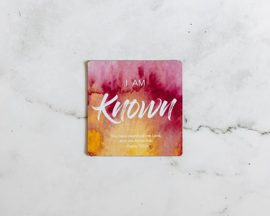 A Red and yellow christian magnet that says I Am Known with a bible verse from Psalm 139:1 on a white marble background that says You have searched me Lord and you know me.