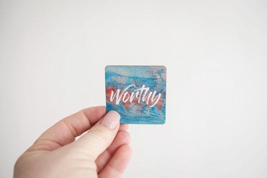 a hand holding a mini affirmation magnet that says worthy