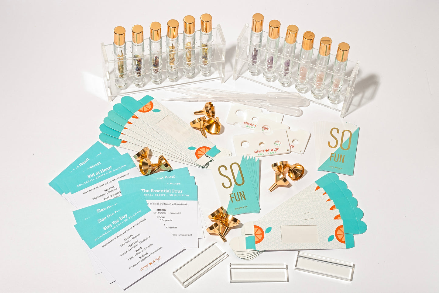 A display of roller bottles with crystals and floral botanicals that come in a diy kit along with cards, pipettes, funnels, boxes, displays, holders and recipe cards