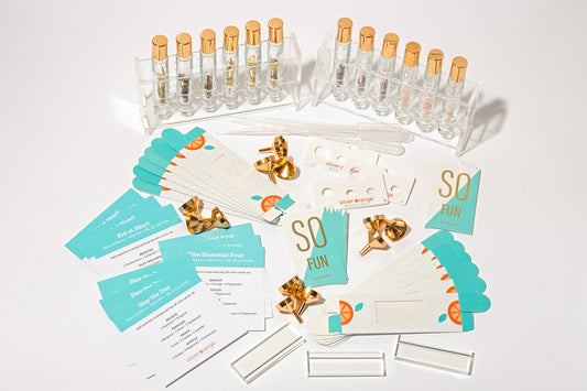 A display of roller bottles with crystals and floral botanicals that come in a diy kit along with cards, pipettes, funnels, boxes, displays, holders and recipe cards