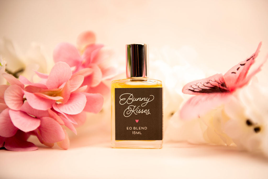 A bottle of Bunny Kisses essential oil blend sitting by flowers and a butterfly