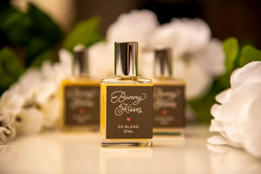 Bottles of Essential oil blends called Bunny Kisses with White flowers in the background