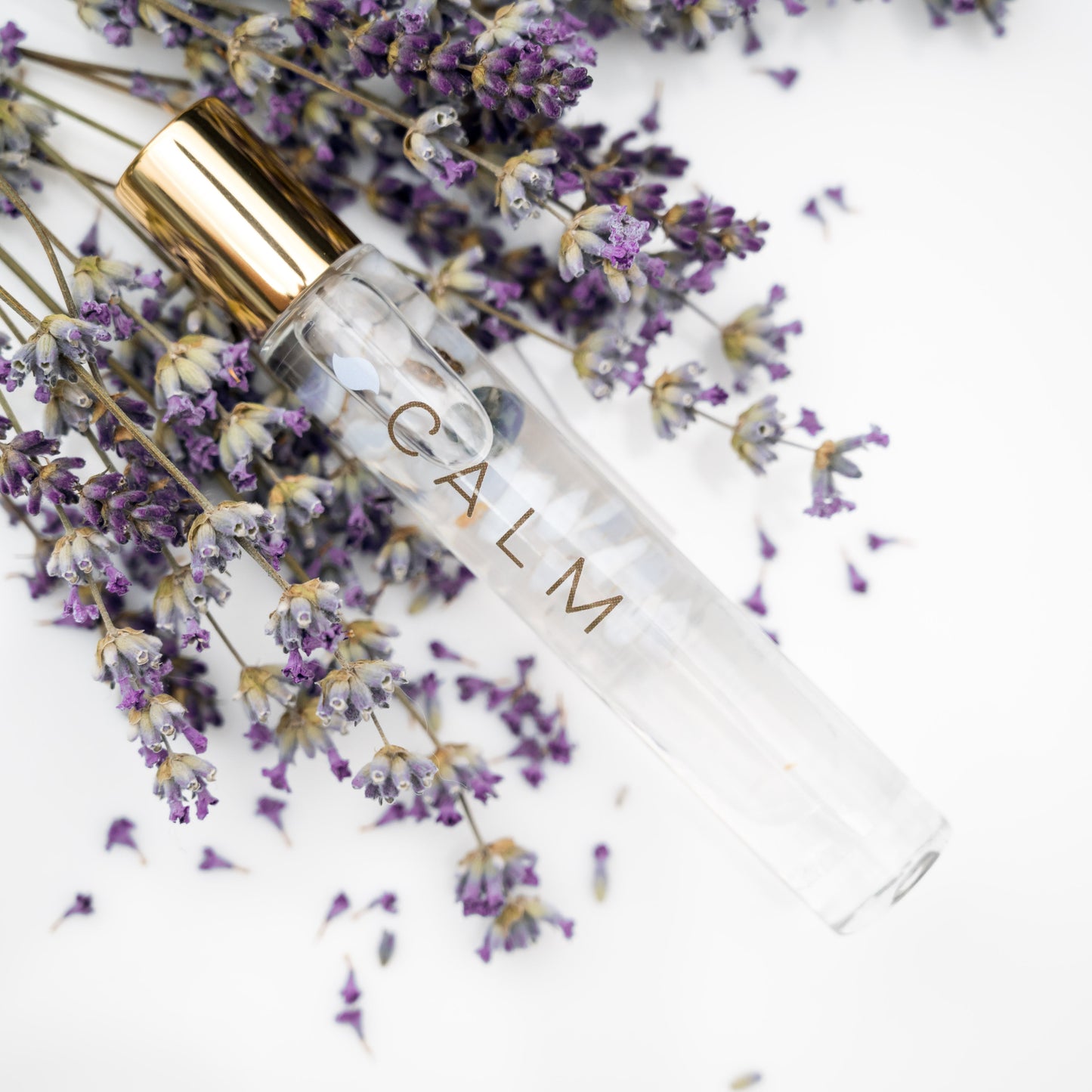 Calm Essential Oil Blend in a Roller bottle with Blue Lace Agate inside laying on sprigs of fresh lavender