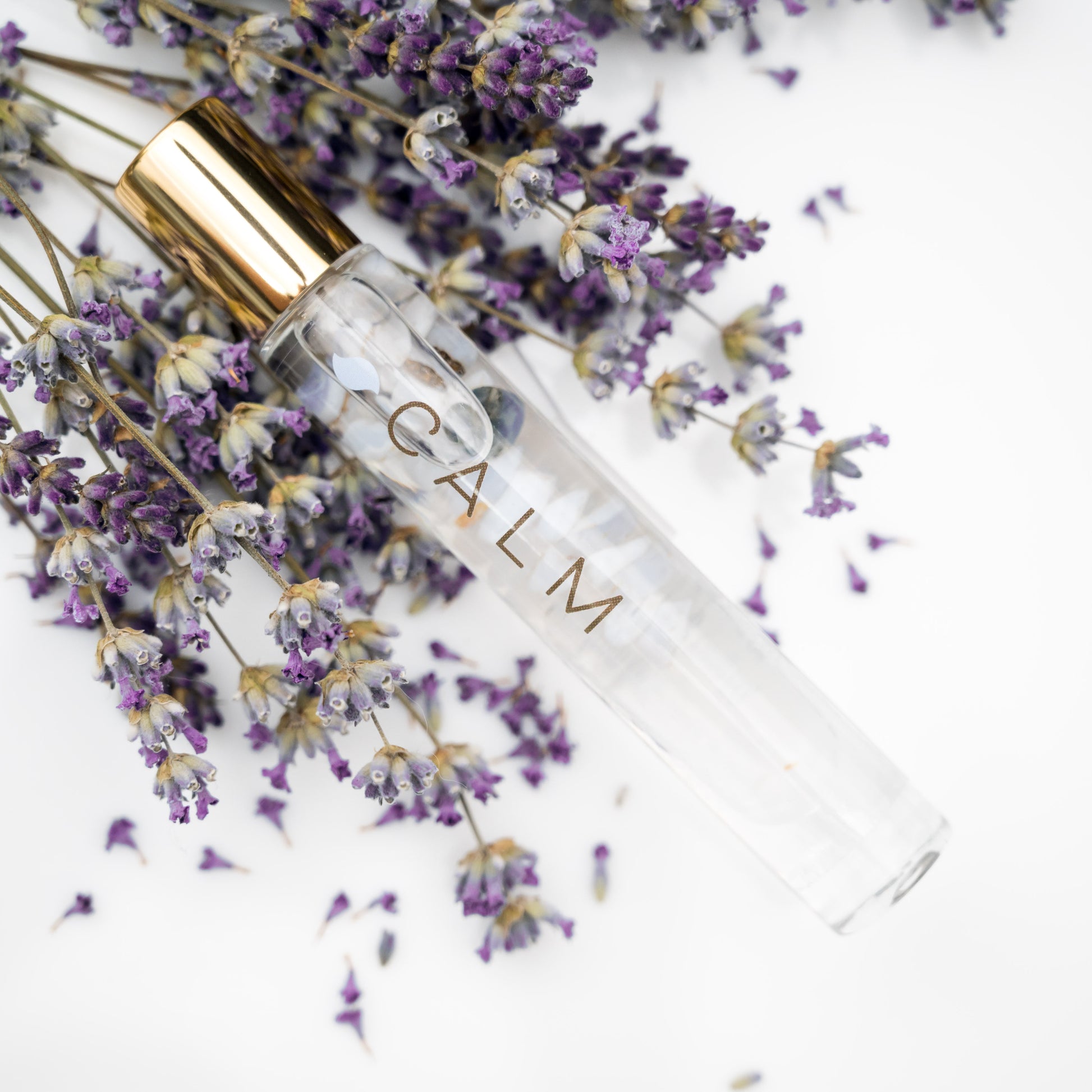 Calm Essential Oil Blend in a Roller bottle with Blue Lace Agate inside laying on sprigs of fresh lavender