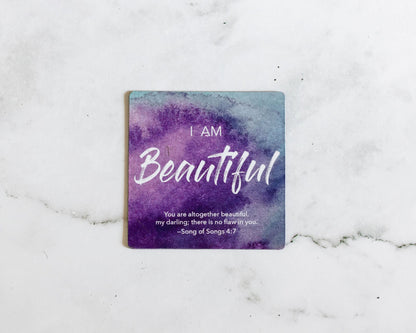 A Purple and Blue Magnet that says I Am Beautiful with a bible verse from Song of Songs 4:7 on a white marble background that says You are altogether beautiful my darling