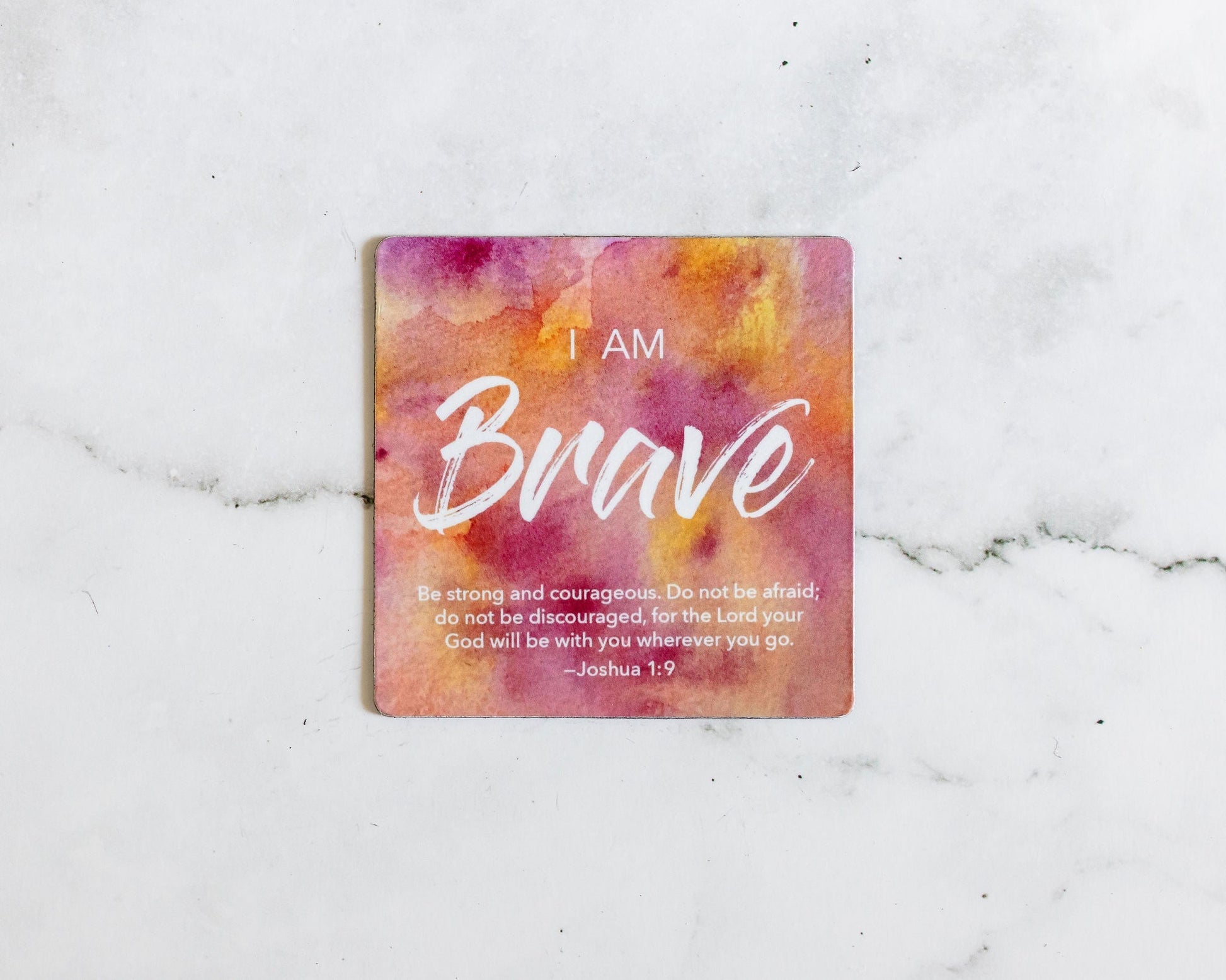 A Pink and Orange magnet that says I Am Brave with a bible verse from Joshua 1:9 on a white marble background that says Be strong an courageous, do not be afraid 