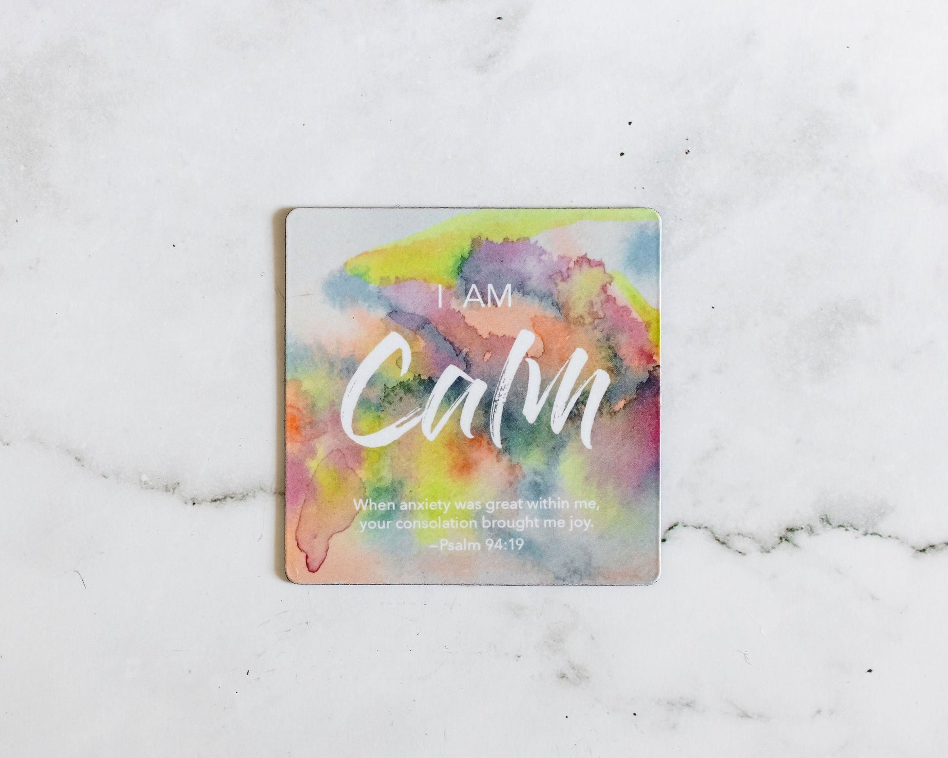 A colorful water color magnet that says I Am Calm with a bible verse from Psalm 94:19 on a white marble background that says When anxiety was great within me your consolation brought me joy
