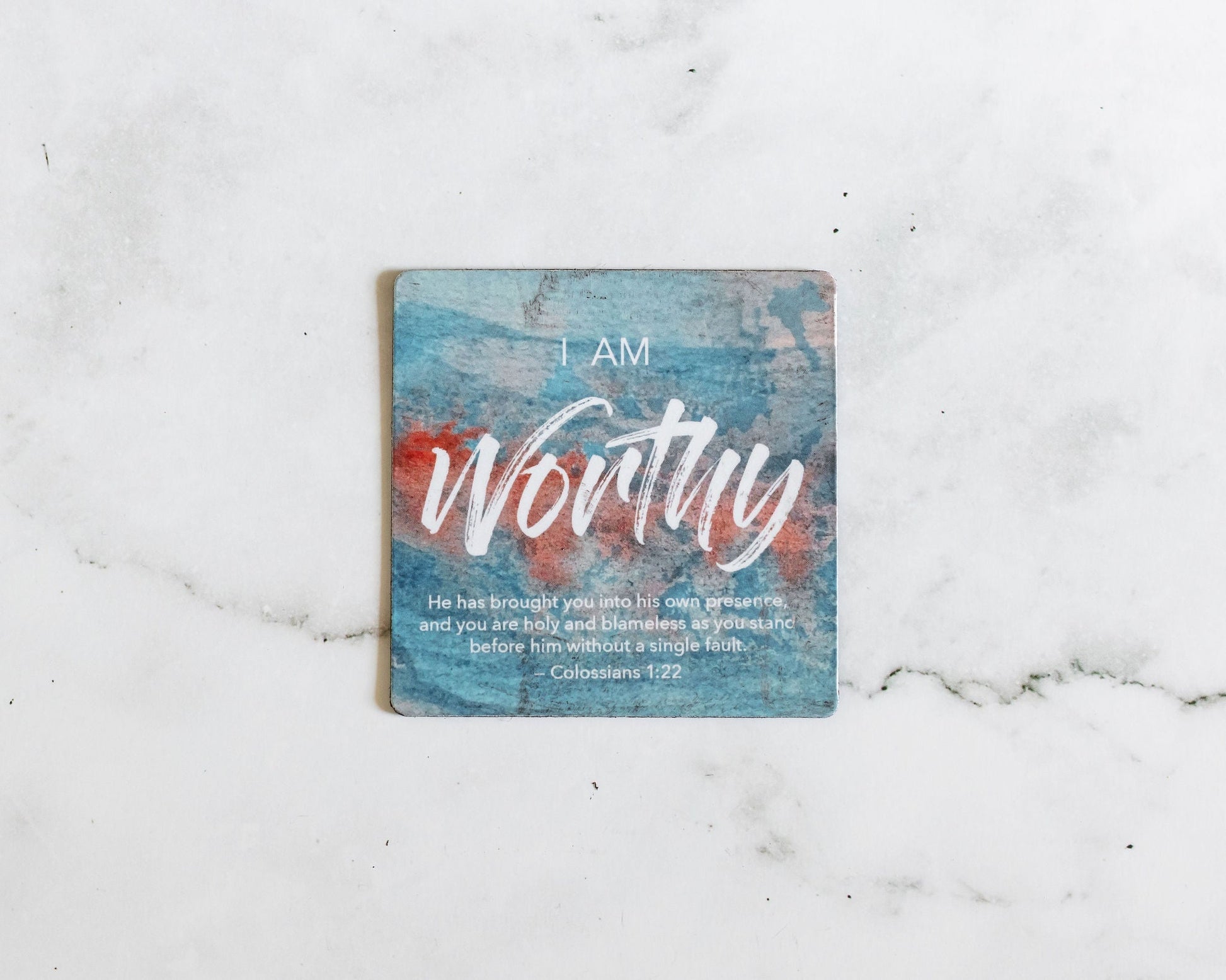 A Blue and red magnet that says I Am Worthy with a bible verse from Colossians 1:22 on a white marble background that says He has brought you into his own presence and you are holy and blameless